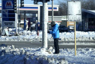 A pedestrian is bundled up as she pushes button for signal sign to cross a street in Buffalo Grove, Ill., Sunday, Jan. 14, 2024. A wind chill warning is in effect as dangerous cold conditions continue in the Chicago area. (AP Photo/Nam Y. Huh)