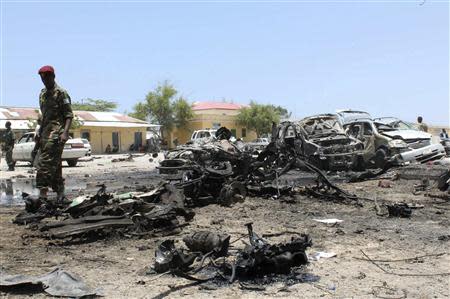 A Somali soldier walks past destroyed vehicles at the scene of a suicide car bombing near a restaurant in Hamaerweyne district in Mogadishu September 7, 2013. A car bomb and suspected suicide bomber struck the restaurant in the Somali capital Mogadishu on Saturday, killing at least 15 people, police said. REUTERS/Feisal Omar