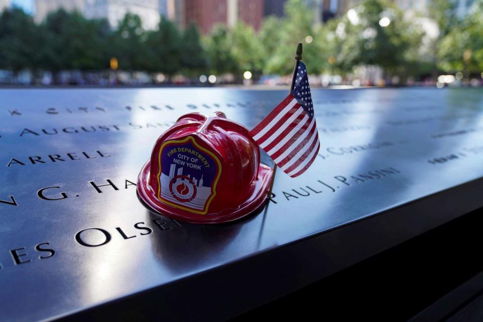 PHOTO: A bronze parapet bearing the names of victims in the 9/11 attacks is adorned with a fire helmet and U.S. national flags at the National September 11 Memorial and Museum in New York, Sept. 10, 2021. (Xinhua News Agency via Getty Ima)