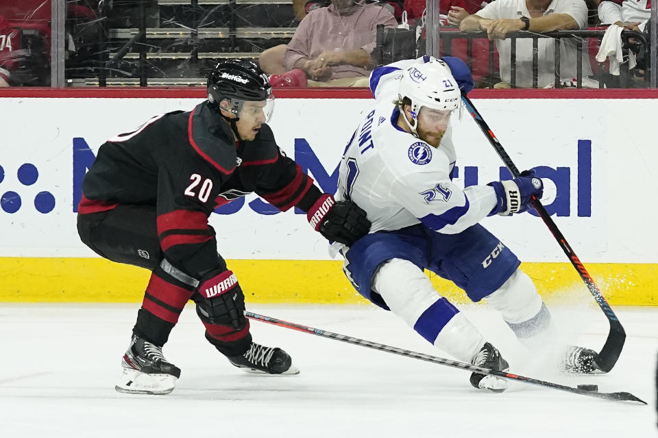Carolina Hurricanes center Sebastian Aho (20) chases Tampa Bay Lightning center Brayden Point (21) during the third period in Game 5 of an NHL hockey Stanley Cup second-round playoff series in Raleigh, N.C., Tuesday, June 8, 2021. (AP Photo/Gerry Broome)