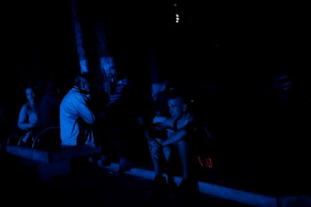 People wait for the power to return at a public square during a blackout in Caracas