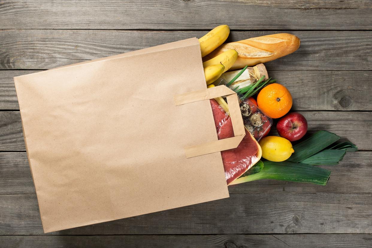 different food in paper bag on wooden background