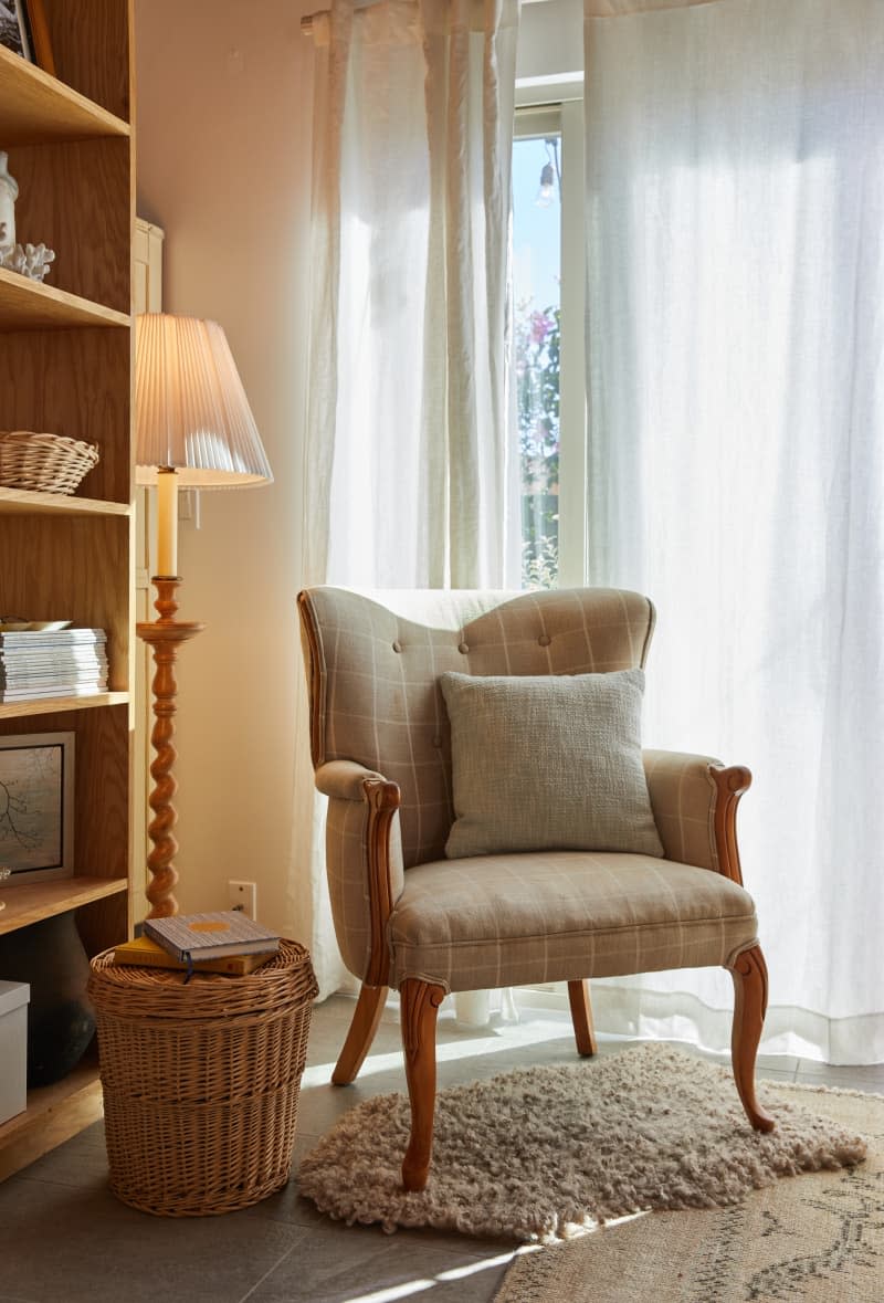 A reading chair sits on a rug next to a wicker basket.