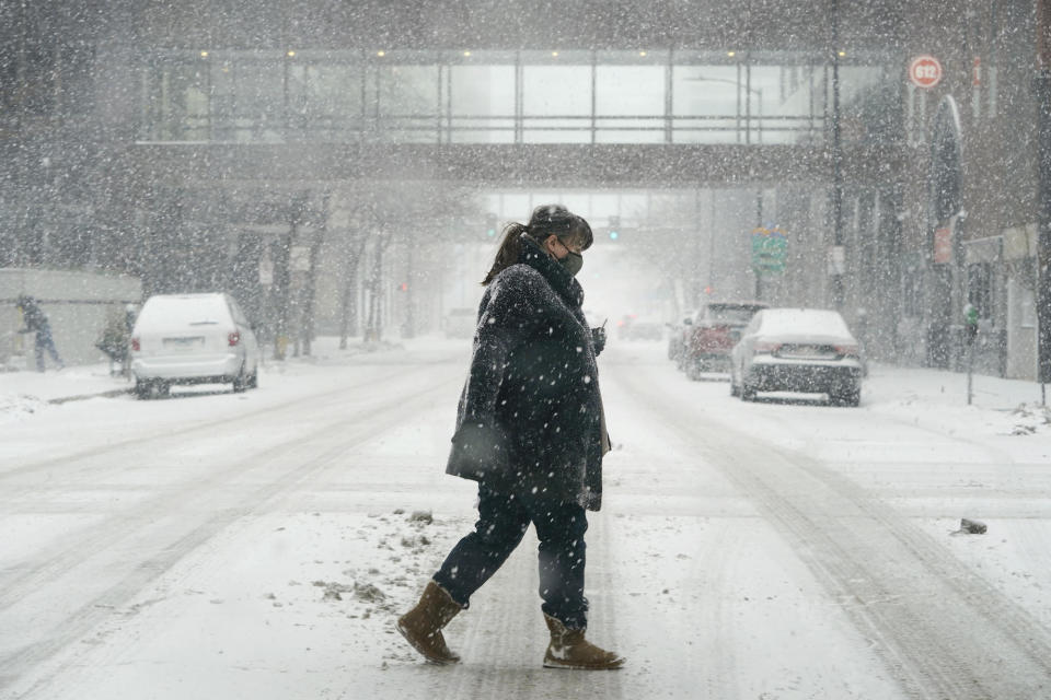 A pedestrian crosses a snow-covered street on January 25, 2021, in Des Moines, Iowa.  / Credit: Charlie Neibergall / AP