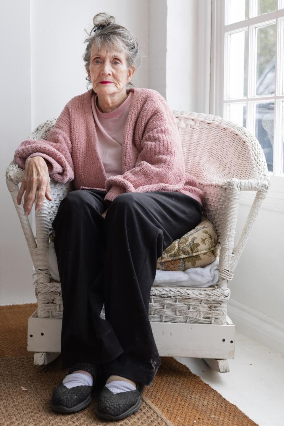 Annie Murphy sits by a window in a wicker chair