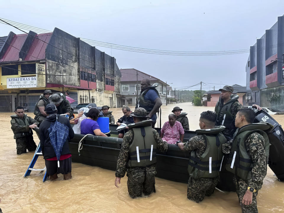 In this photo released by National Disaster Management Agency, the army evacuate residents on Chaah town in Segamat, in southern Johor state, Malaysia, Wednesday, March 1, 2023. Rescuers in boats plucked flood victims trapped on rooftops and hauled others to safety as incessant rain submerged homes and villages in parts of Malaysia, leading to over 26,000 people evacuated as of Thursday. (National Disaster Management Agency via AP)