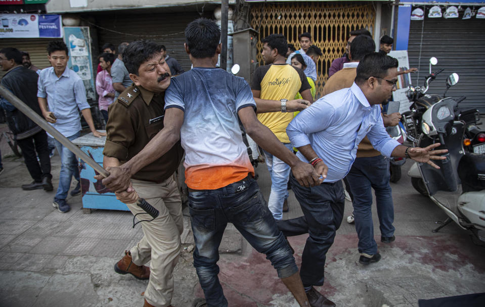 A policemen clashes with protestors demonstrating against the Citizenship Amendment Bill (CAB) in Gauhati, India, Wednesday, Dec. 11, 2019. Protesters burned tires and blocked highways and rail tracks in India's remote northeast for a second day Wednesday as the upper house of Parliament began debating legislation that would grant citizenship to persecuted Hindus and other religious minorities from Pakistan, Bangladesh and Afghanistan. (AP Photo/Anupam Nath)