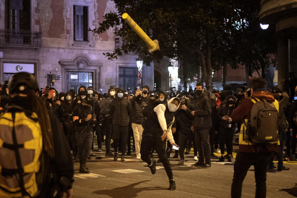 Un hombre lanza una señal de tránsito contra los agentes de la policía durante una manifestación que se tornó violenta el domingo 21 de febrero de 2021, en Barcelona. (AP Foto/Emilio Morenatti)