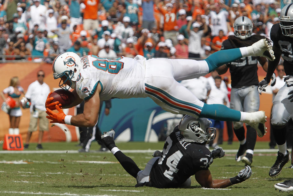 Miami Dolphins' Anthony Fasano leaps into th eendzone to score at the expense of Oakland Raiders' Mike Mitchell during their NFL football game in Miami Gardens, Florida September 16, 2012. REUTERS/Andrew Innerarity (UNITED STATES - Tags: SPORT FOOTBALL)