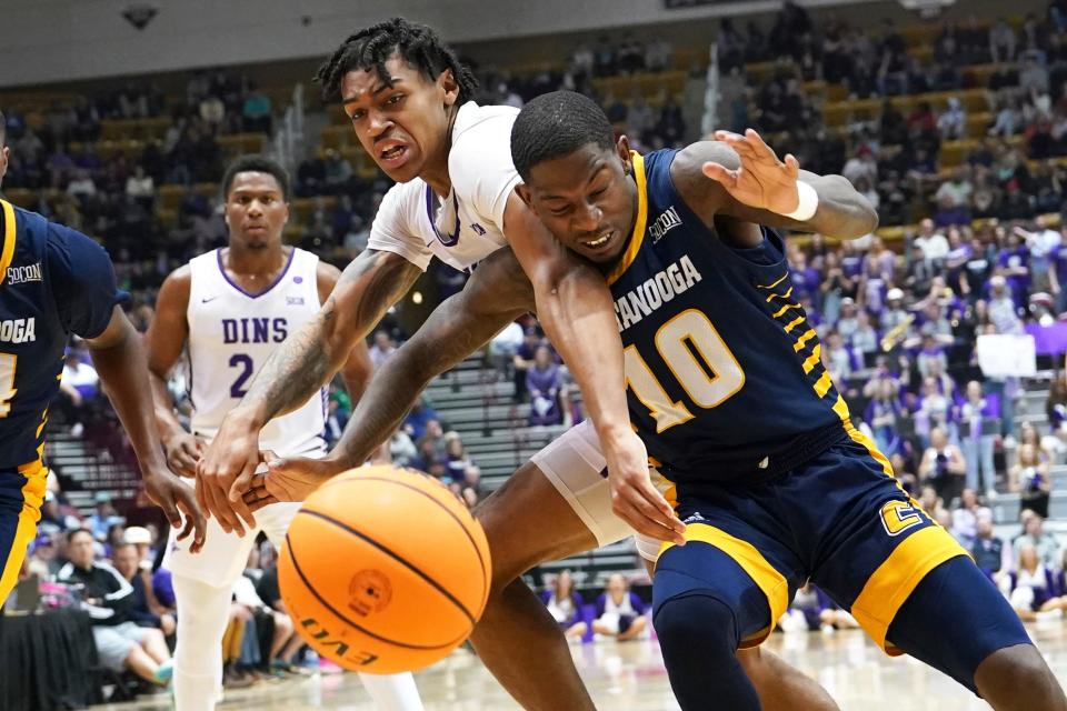 Furman forward Tyrese Hughey and Chattanooga guard Dalvin White (10) battle for a loose ball during the first half of an NCAA men's college basketball championship game for the Southern Conference tournament, Monday, March 6, 2023, in Asheville, N.C. (AP Photo/Kathy Kmonicek)