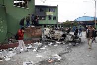 Personas caminan a lado de un auto incendiado tras la salida del país del renunciado presidente Evo Morales en La Paz