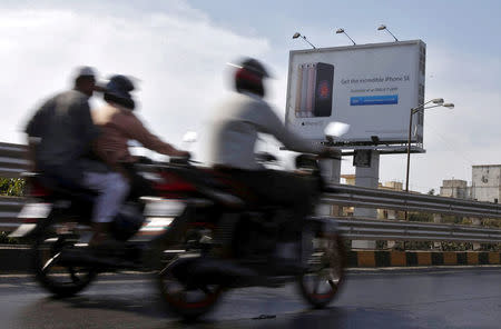 FILE PHOTO: Men ride on motorbikes past an Apple iPhone advertisement billboard in Mumbai, India, April 26, 2016. REUTERS/Shailesh Andrade/File Photo