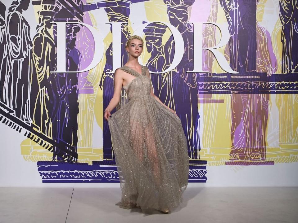 Anya Taylor Joy poses in a semi-sheer dress at a Dior fashion show.