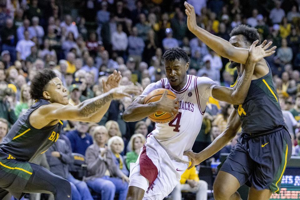 Arkansas guard Davonte Davis (4) drives between Baylor defenders Keyonte George, left, and LJ Cryer, right, during the second half of an NCAA college basketball game in Waco, Texas, Saturday, Jan. 28, 2023. (AP Photo/Gareth Patterson)