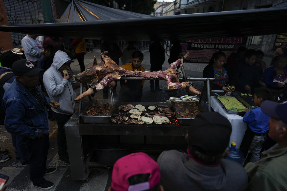 Protestors consume a roast a pig in front of the police near the Congress building in Guatemala City, Tuesday, Nov. 28, 2023. Protestors have taken to the streets for weeks demanding de resignation of Attorney General Consuelo Porras after her office intervened in the electoral process on several occasions. (AP Photo/Moises Castillo)