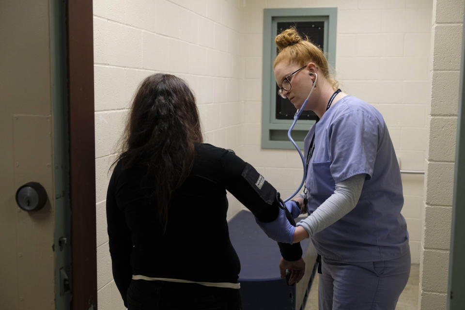 In this Tuesday, April 16, 2019, photo, Emma Elwood, a nurse at the Lake County Jail in Lakeport, Calif., checks the vitals of a woman in the booking area. A series of changes, including adding a registered nurse, were made at the jail following the 2015 suicide of Elizabeth Gaunt, a former social worker who had repeatedly cried for help while locked in a cell. A wrongful death lawsuit resulted in a $2 million settlement. (AP Photo/Eric Risberg)