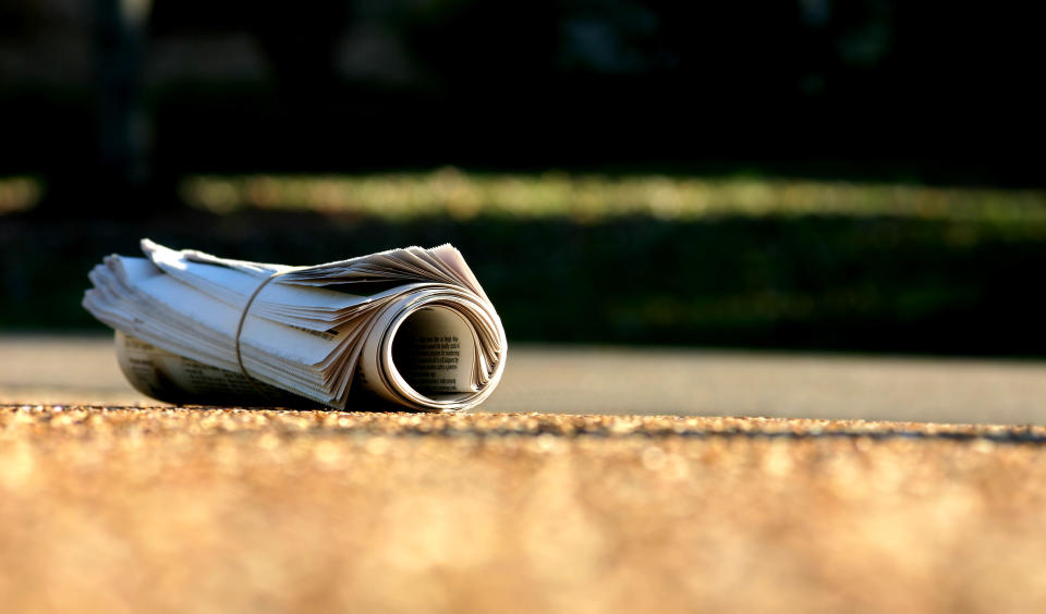 Image of newspaper rolled up on street as News Corp stops printing 100 regional mastheads