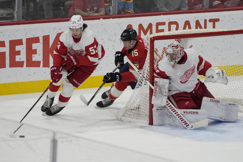 Detroit Red Wings defenseman Moritz Seider (53) and Florida Panthers center Anton Lundell (15) go after the puck as goaltender Alex Lyon (34) protects the net during first period an NHL hockey game, Wednesday, Jan. 17, 2024, in Sunrise, Fla. (AP Photo/Marta Lavandier)