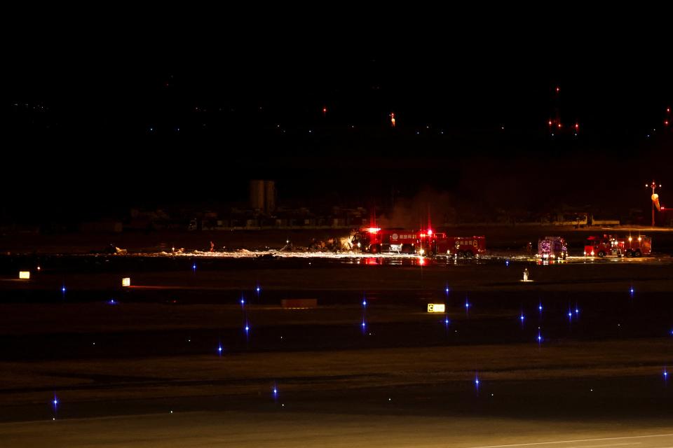 Firefighters work on remnants of a Coast Guard aircraft at Haneda International Airport (Reuters)