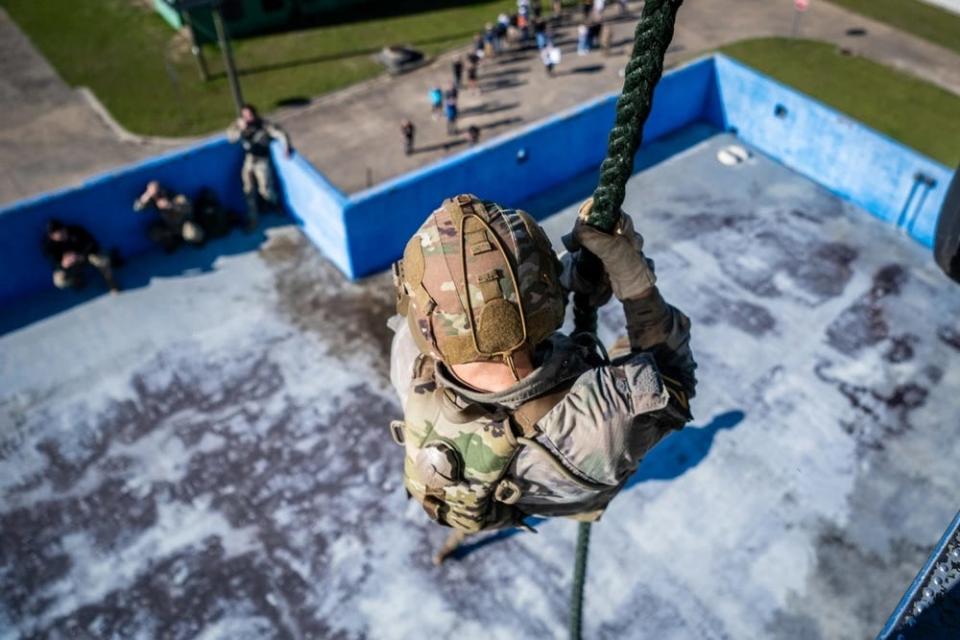 A US Army soldier propels down a rope from a UH-60 Blackhawk helicopter during an urban operations event.