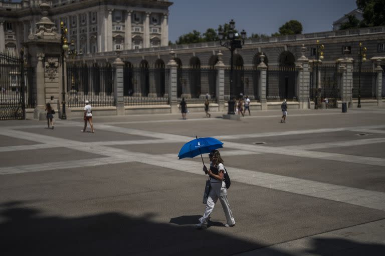 Una mujer se protege del sol con una sombrilla frente al Palacio Real durante un caluroso día soleado en Madrid, España, el lunes 18 de julio de 202