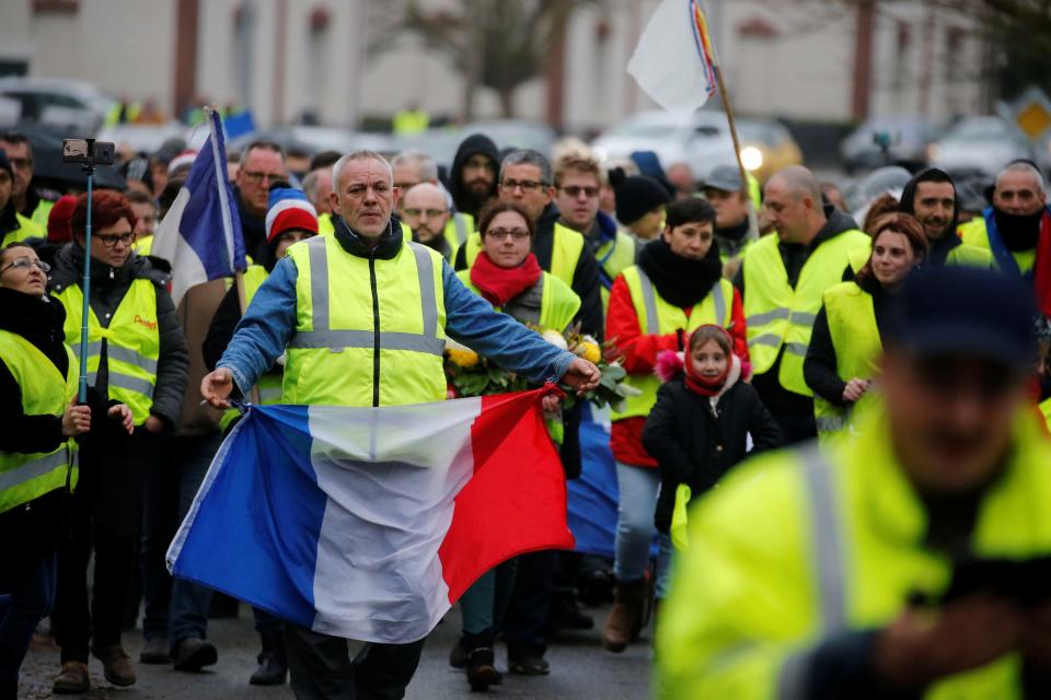 A protester wearing a yellow vest holds a French flag during a demonstration by the 