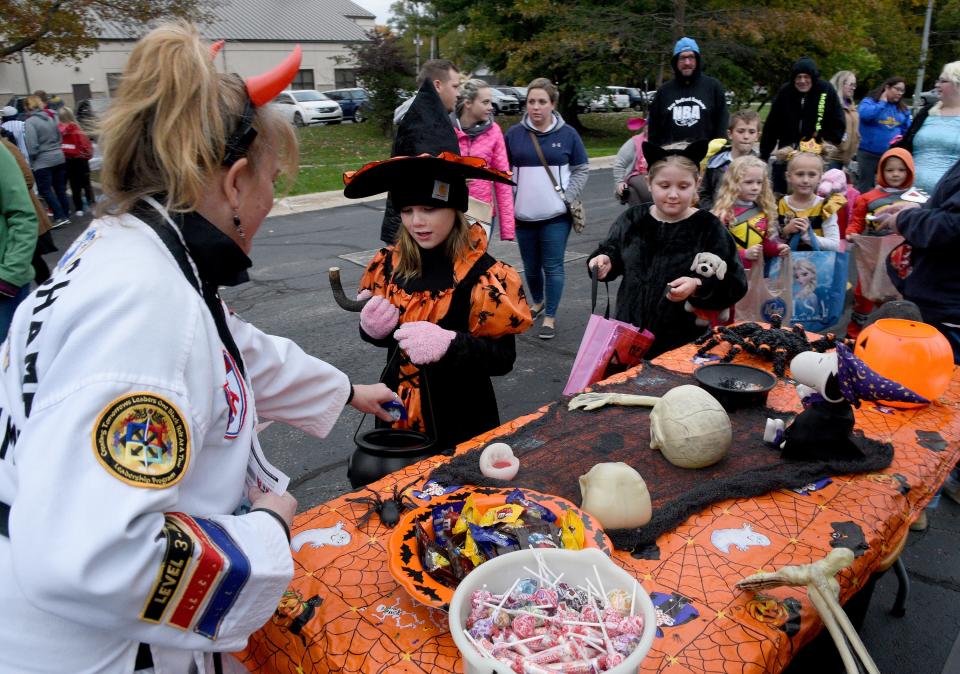 Mary Jo Feldkamp, head instructor for Temperance ATA Martial Arts, gives candy to Autumn Walerius, then 7, dressed as a witch, and Kaleigh Mack, then 8, dressed as a cat, at a previous trunk-or-treat at the Bedford Branch Library. Several trunk-or-treat events and other fall and Halloween activities are planned this season throughout the county.