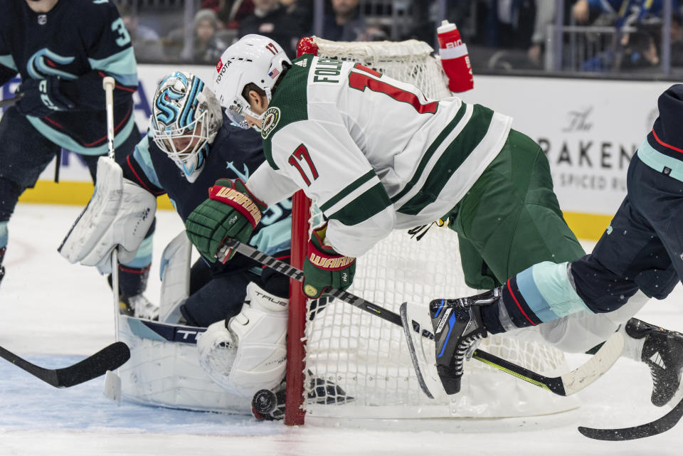 Seattle Kraken goalie Martin Jones, left, keeps the puck out of the goal, next to Minnesota Wild forward Marcus Foligno during the first period of an NHL hockey game Friday, Nov. 11, 2022, in Seattle. (AP Photo/Stephen Brashear)