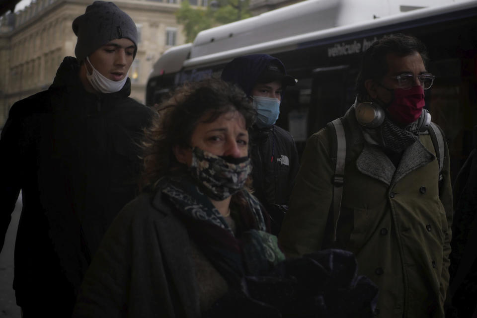 People wear masks as they walk in a street of Paris, Tuesday, Oct. 27, 2020. France's government is holding emergency virus control meetings Tuesday and warning of possible new lockdowns, as hospitals fill up with new COVID patients and doctors plead for backup. (AP Photo/Thibault Camus)