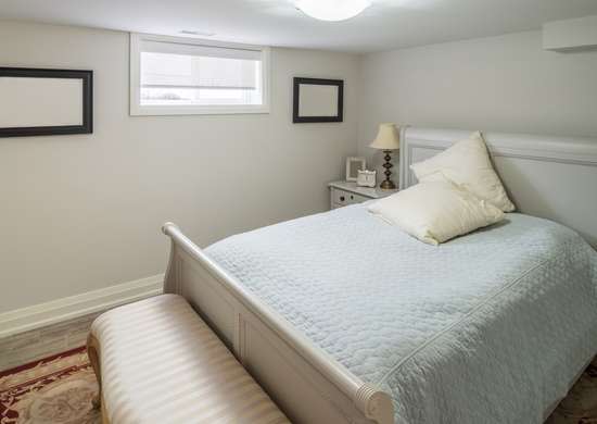 A low-light basement bedroom with one small window.