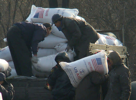 FILE PHOTO - Workers unload food aid from a truck in the Sinuiju region of North Korea in this picture taken on December 11, 2008 from a tourist boat on the Yalu River, which divides North Korea and China. REUTERS/Stringer/File Photo