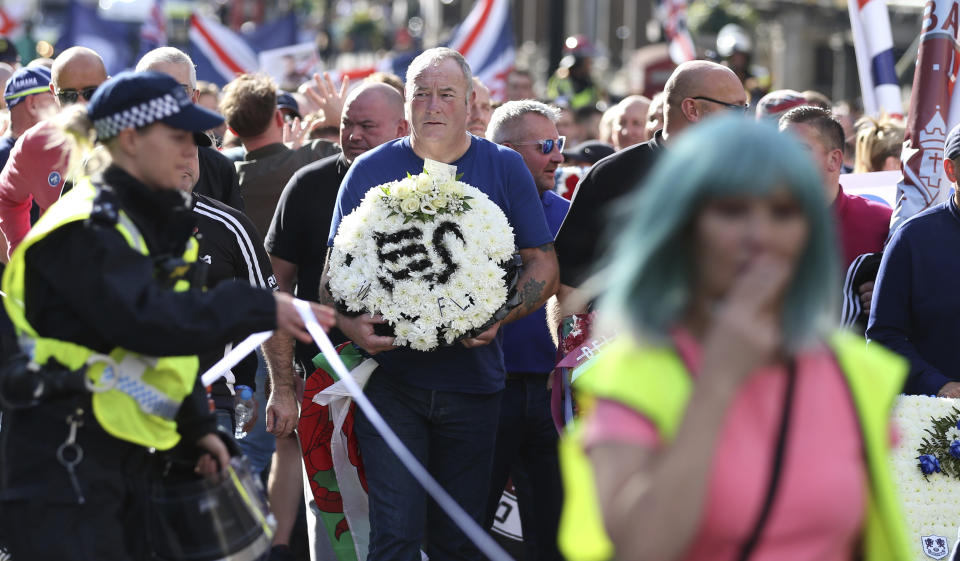 A man holds a floral depiction of a soccer clubs badge as he takes part in a march by the Football Lads Alliance march in London, Saturday, Oct. 13, 2018. (AP Photo/Alastair Grant)