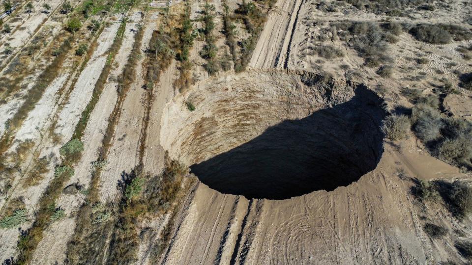 TOPSHOT - Aerial view taken on August 1, 2022, showing a large sinkhole that appeared over the weekend near the mining town of Tierra Amarilla, Copiapo Province, in the Atacama Desert in Chile. - A 100-metre security perimeter has been erected around the hole which appeared in the Tierra Amarilla municipality near the Alcaparrosa mine operated by Canadian firm Lundin Mining. (Photo by JOHAN GODOY / AFP) (Photo by JOHAN GODOY/AFP via Getty Images)