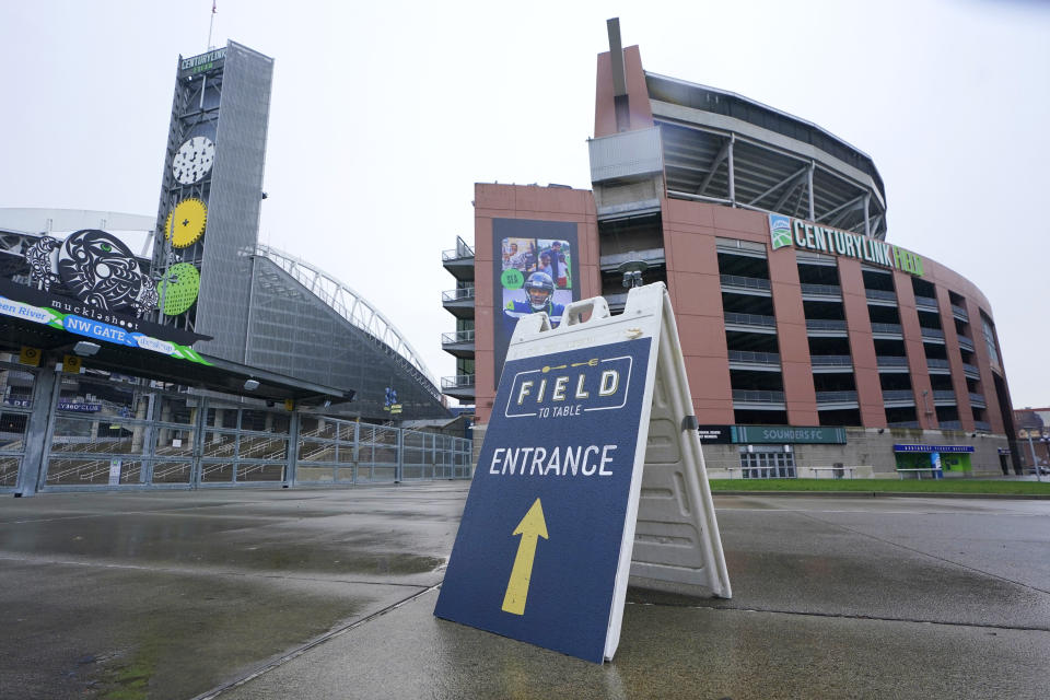 A sign directs customers arriving for the "Field To Table" event to an entrance at Lumen Field (formerly CenturyLink Field) the home of the Seattle Seahawks NFL football team, Thursday, Feb. 18, 2021, in Seattle. Thursday was the first night of several weeks of dates that offer four-course meals cooked by local chefs and served on the field at tables socially distanced as a precaution against the COVID-19 pandemic, which has severely limited options for dining out at restaurants in the area. (AP Photo/Ted S. Warren)