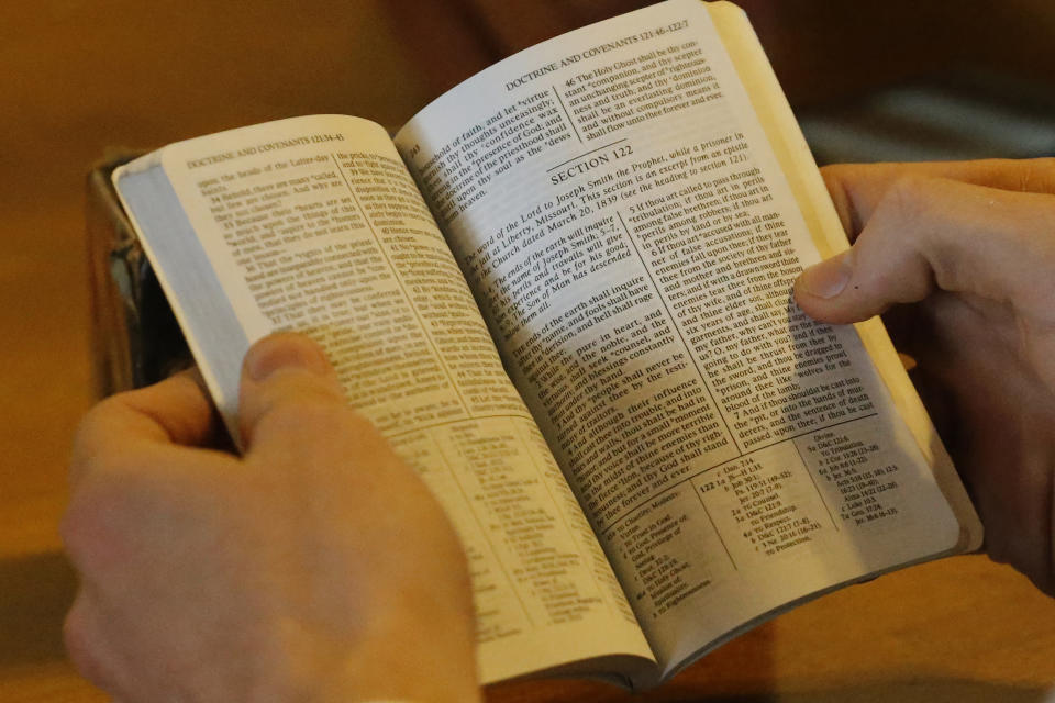 In this May 27, 2020, photo, Andrew Zitting, a missionary with The Church of Jesus Christ of Latter-day Saints, looks at the Doctrine and Covenants at the kitchen table at his apartment, in Brigham City, Utah. After hastily bringing home 26,000 young men and women who were serving in foreign countries, the faith has begun sending many of them out again in their home countries with a new focus on online work that could stick even when the pandemic is over, church officials told The Associated Press. (AP Photo/Rick Bowmer)