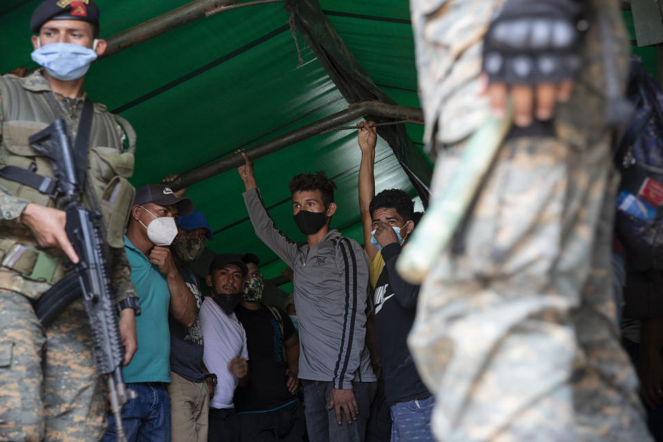 Migrantes hondureños de pie en un vehículo del ejército guatemalteco antes de regresar a su hogar, el sábado 3 de octubre de 2020, en Morales, Guatemala. (AP Foto/Moises Castillo)