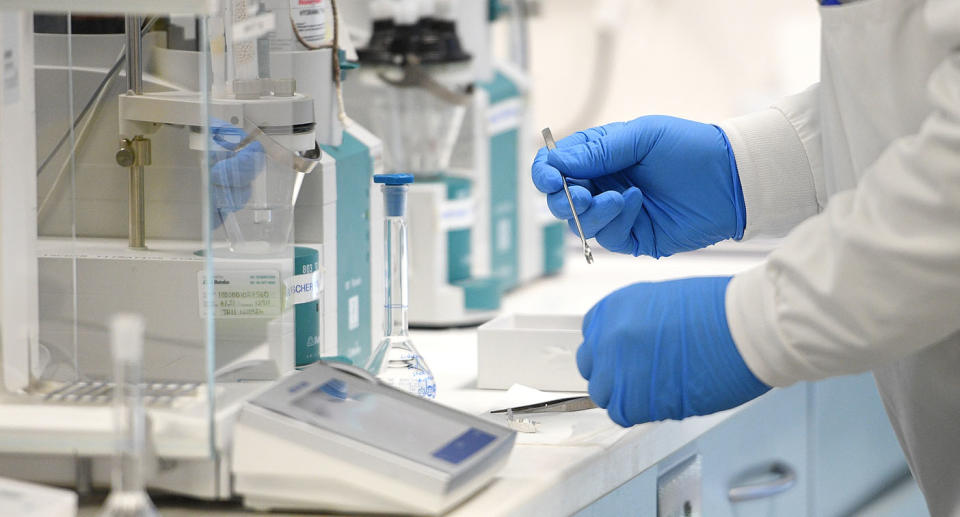 Researchers hands in lab shown working on vaccine.