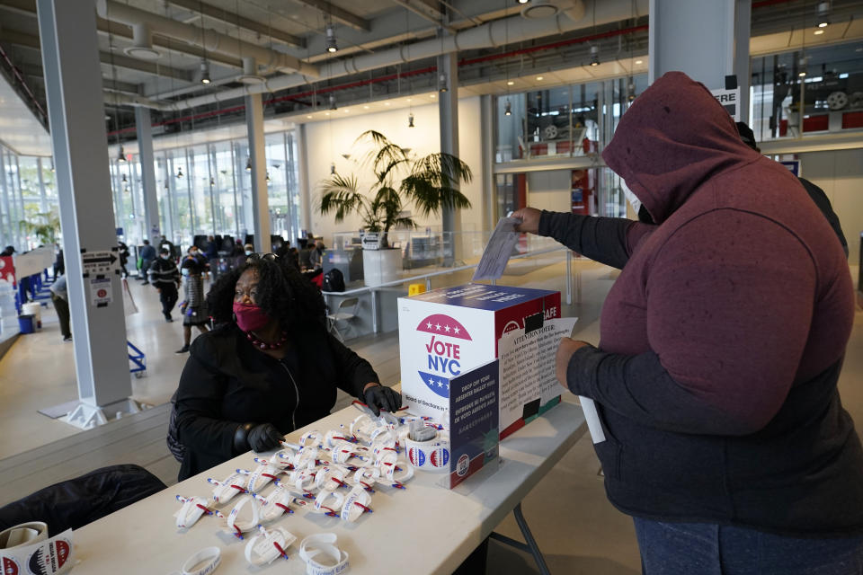 A voter drops his absentee ballot into a box at a special table set aside for that purpose on the last day of early voting, Sunday, Nov. 1, 2020, at Columbia University's Forum in the West Harlem neighborhood of New York. (AP Photo/Kathy Willens)