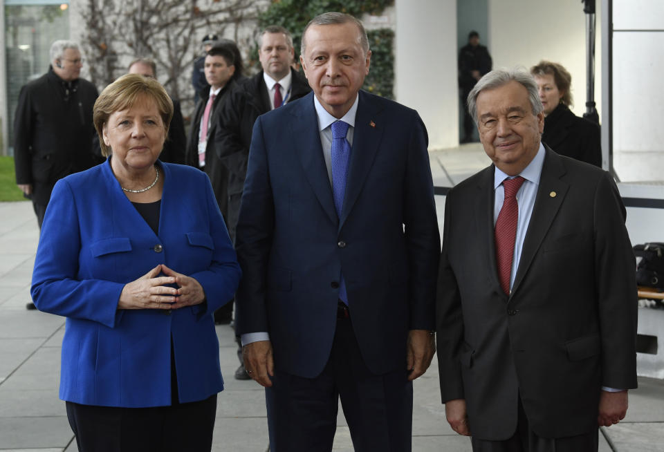 German Chancellor Angela Merkel, left, greets United Nations Secretary General Antonio Guterres, right, and Turkish President Recep Tayyip Erdogan, center, during arrivals for a conference on Libya at the chancellery in Berlin, Germany, Sunday, Jan. 19, 2020. German Chancellor Angela Merkel hosts the one-day conference of world powers on Sunday seeking to curb foreign military interference, solidify a cease-fire and help relaunch a political process to stop the chaos in the North African nation. (AP Photo/Jens Meyer)