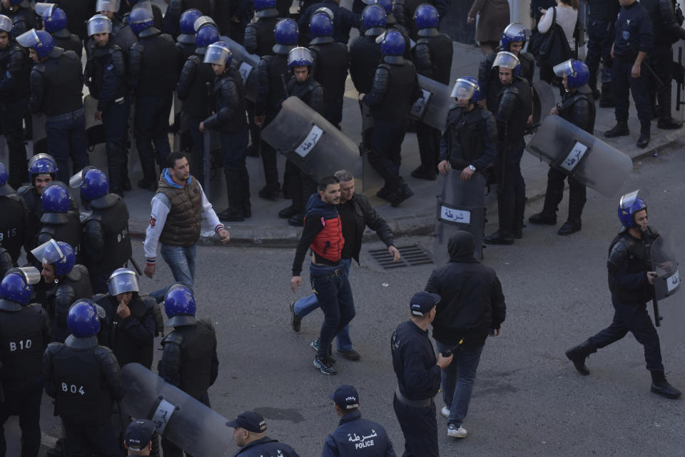 Security forces arrest a man as protesters take to the streets in the capital Algiers to protest against the government and reject the upcoming presidential elections, in Algeria, Wednesday, Dec. 11, 2019. Algeria's powerful army chief promises that a presidential election on Thursday will define the contours of a new era for a nation where the highest office has stood vacant for eight months. The tenacious pro-democracy movement which forced leader Abdelaziz Bouteflika to resign after 20 years in power doesn't trust the confident claim and is boycotting the vote. (AP Photo/Toufik Doudou)