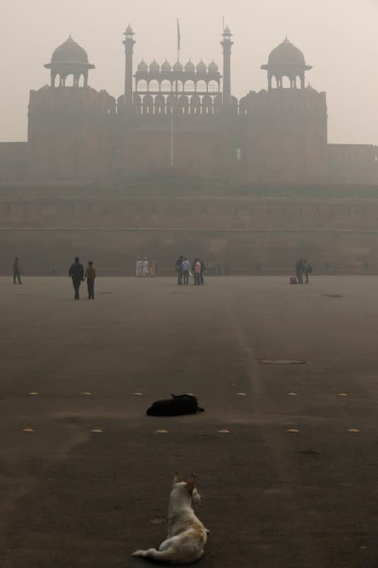 People walk outside the Red Fort on a smoggy morning in the old quarters of Delhi