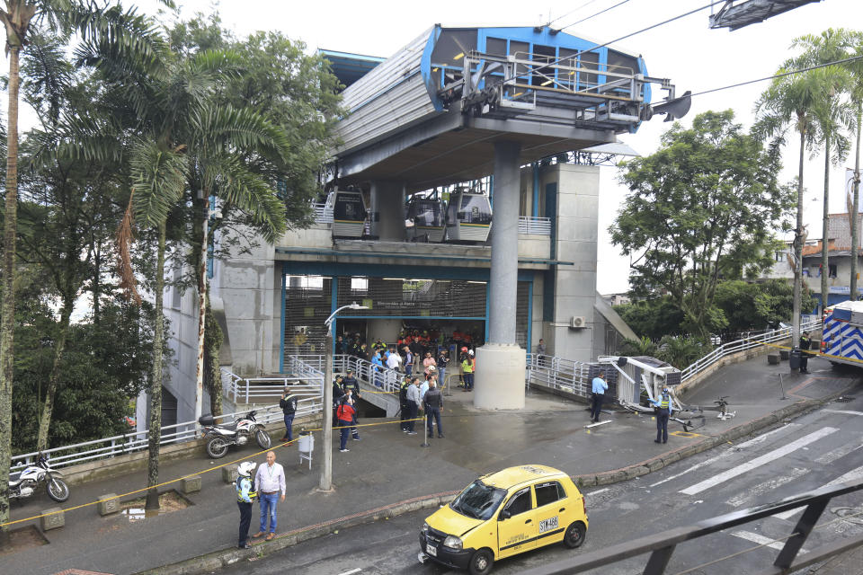 A cable car lays on the ground, right, after it fell in Medellin, Colombia, Wednesday, June 26, 2024. At least one person was killed and 12 others were injured when the cable car collapsed while approaching a station, local authorities said. (AP Photo/Fredy Amariles)