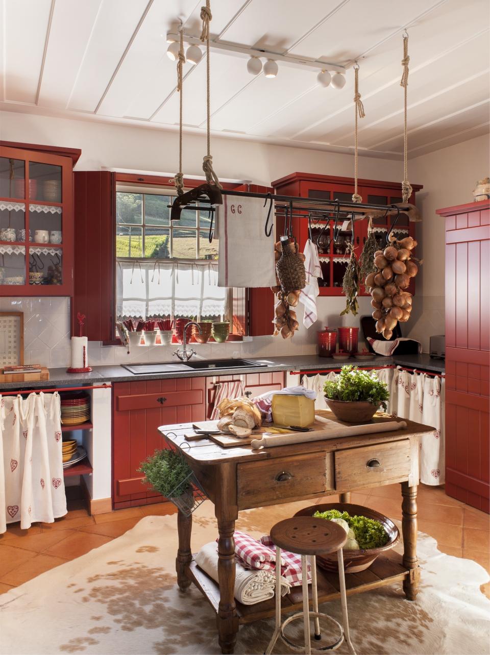 <p> With the gourmet status of Gallic cuisine, it's no surprise that French country kitchens put food front and centre.  </p> <p> 'The tomato red color was the guiding thread of this house and is also present in this kitchen. It's a color that is very typical in traditional kitchens and also recalls antique kitchen cloths and linens,' suggests interior designer Joana Aranha. </p> <p> 'Besides all this, it was in the local markets that we took the inspiration for the organization of the kitchen with hanging onions and aromatic herbs scattered throughout the space. We even designed some shelves slatted underneath to keep the vegetables in plain sight, ensuring that they last longer. This is a place to actually cook – a real and warm country kitchen.' </p>
