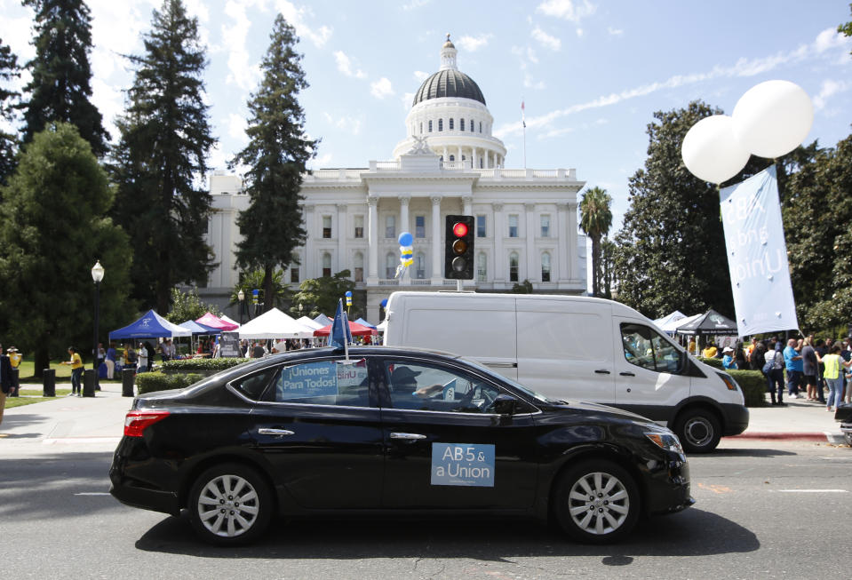 FILE - In this Aug. 28, 2019, file photo, dozens of supporters of a measure to limit when companies can label workers as independent contractors circle the Capitol during a rally in Sacramento, Calif. Gov Gavin Newsom signed the bill AB5 by Assemblywoman Lorena Gonzalez, D-San Diego, aimed at giving wage and benefit protections to ride share drivers and workers in other industries on Wednesday, Sept. 18, 2019. (AP Photo/Rich Pedroncelli, File)