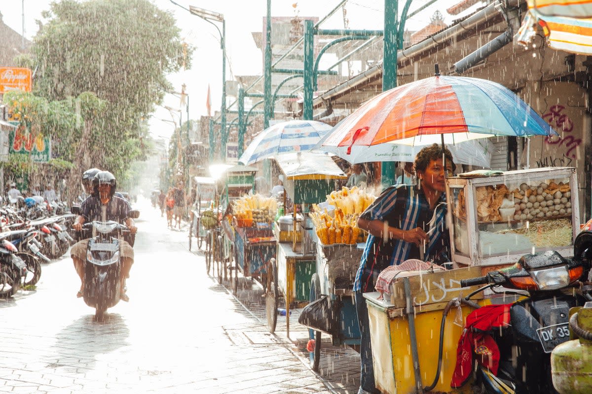 Street vendors in Kuta shelter from a downpour (Getty Images)