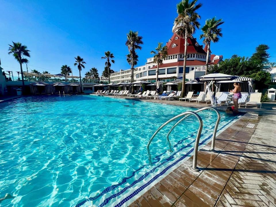 the entry steps to a pool next to a white building with a red roof.