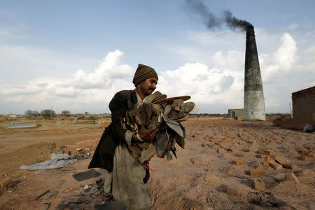 A worker carries shoes to be burned in the kiln of a brick factory in Islamabad, Pakistan March 9, 2017. REUTERS/Caren Firouz