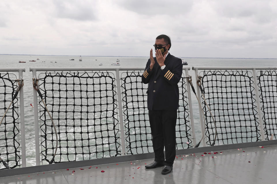 An Indonesian pilot prays during a memorial ceremony for the victims of Sriwijaya Air flight SJ-182 on the deck of Indonesian Navy Ship KRI Semarang that sails in the Java Sea where the plane crashed on Jan. 9 killing all of its passengers, near Jakarta in Indonesia, Friday, Jan. 22, 2021. (AP Photo/Tatan Syuflana)