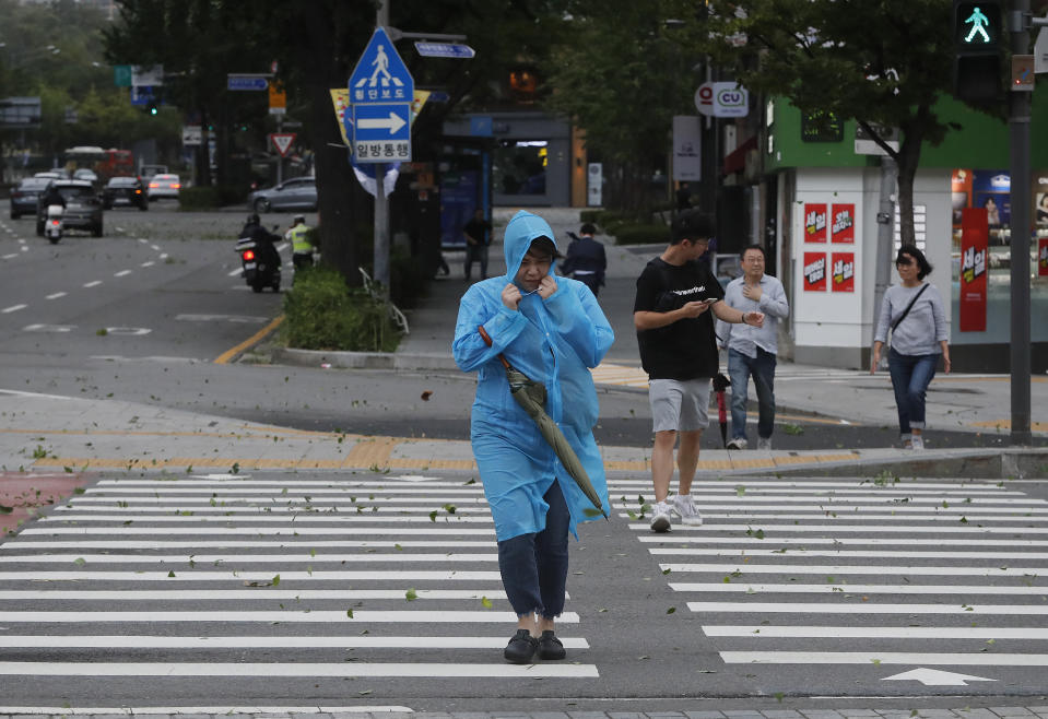 A woman struggles against the strong wind caused by Typhoon Lingling in Seoul, South Korea, Saturday, Sept. 7, 2019. The typhoon passed along South Korea's coast Saturday, toppling trees, grounding planes and causing at least two deaths before the storm system made landfall in North Korea. (AP Photo/Ahn Young-joon)