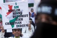 A young demonstrator holds a sign during a protest against a new citizenship law on the outskirts of Mumbai